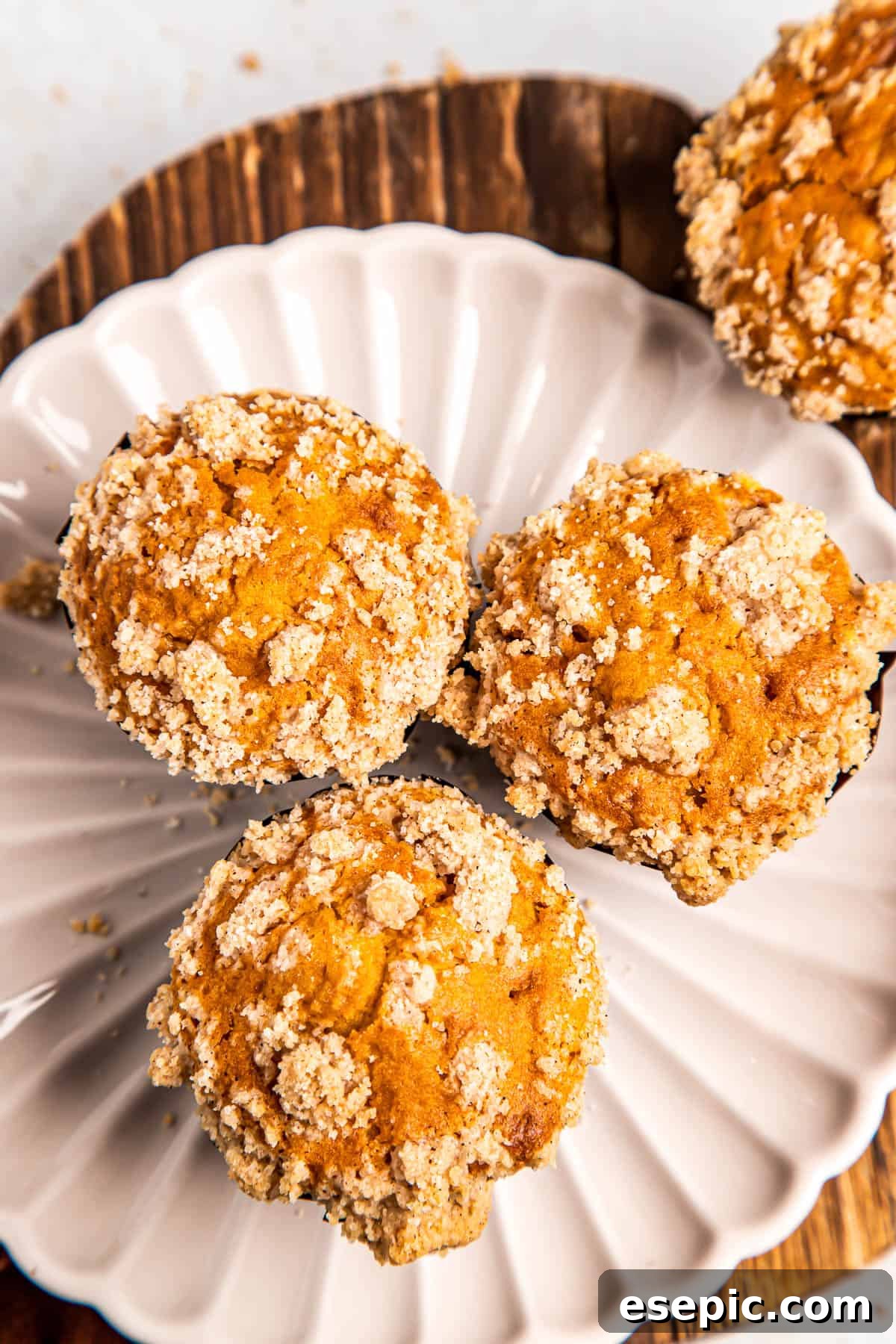 An inviting overhead shot of three perfectly baked pumpkin muffins arranged on a clean white plate, highlighting their golden-brown tops and rich texture.