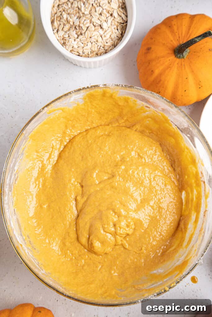 Close-up shot of pumpkin muffin batter in a mixing bowl, showcasing its rich, autumnal color and smooth texture, ready for baking.