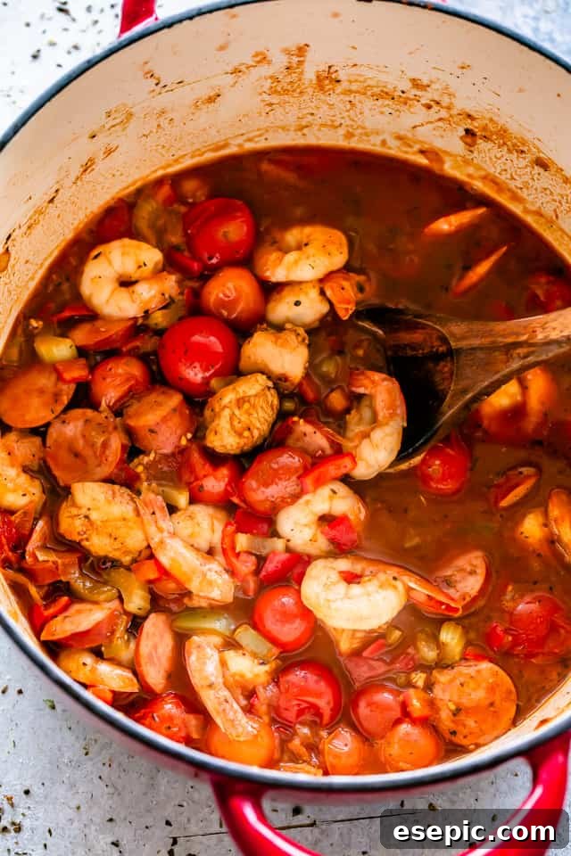 Shrimp, Chicken, and Sausage cook together in a large pot with sauce.