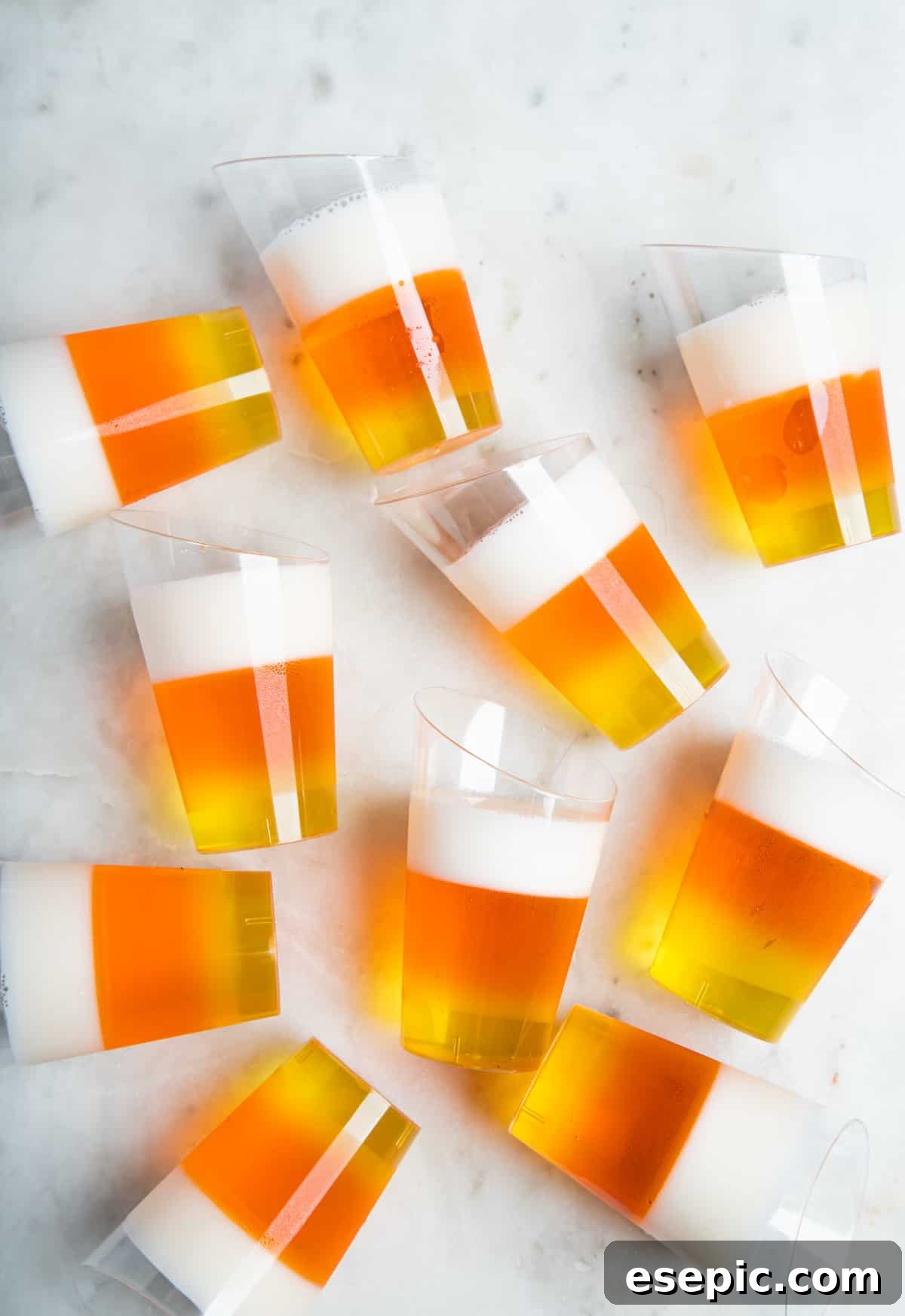 A collection of colorful candy corn jello shots arranged on a white table, ready for a Halloween party.