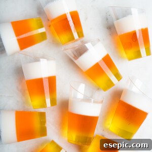 A collection of colorful candy corn jello shots arranged on a white table, ready for a Halloween party.