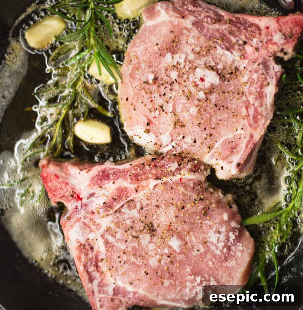 Roasted Pork Chops with Apples and Root Vegetables 4 Searing pork chops in a skillet with garlic and rosemary, achieving a golden-brown crust.