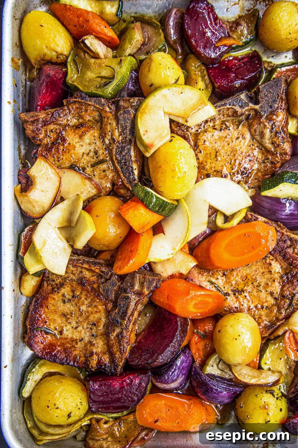 Roasted Pork Chops with Apples and Root Vegetables 6 A close-up overhead shot of the baking dish with perfectly cooked pork chops, caramelized apples, and tender vegetables infused with apple juice and rosemary.