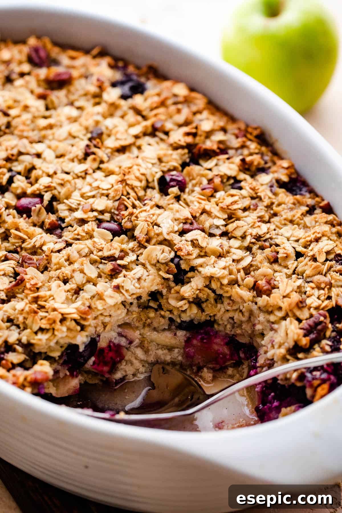 Warm Apple Blueberry Oatmeal Bake 3 a white baking dish with baked oatmeal filled with apples and studded with blueberries.