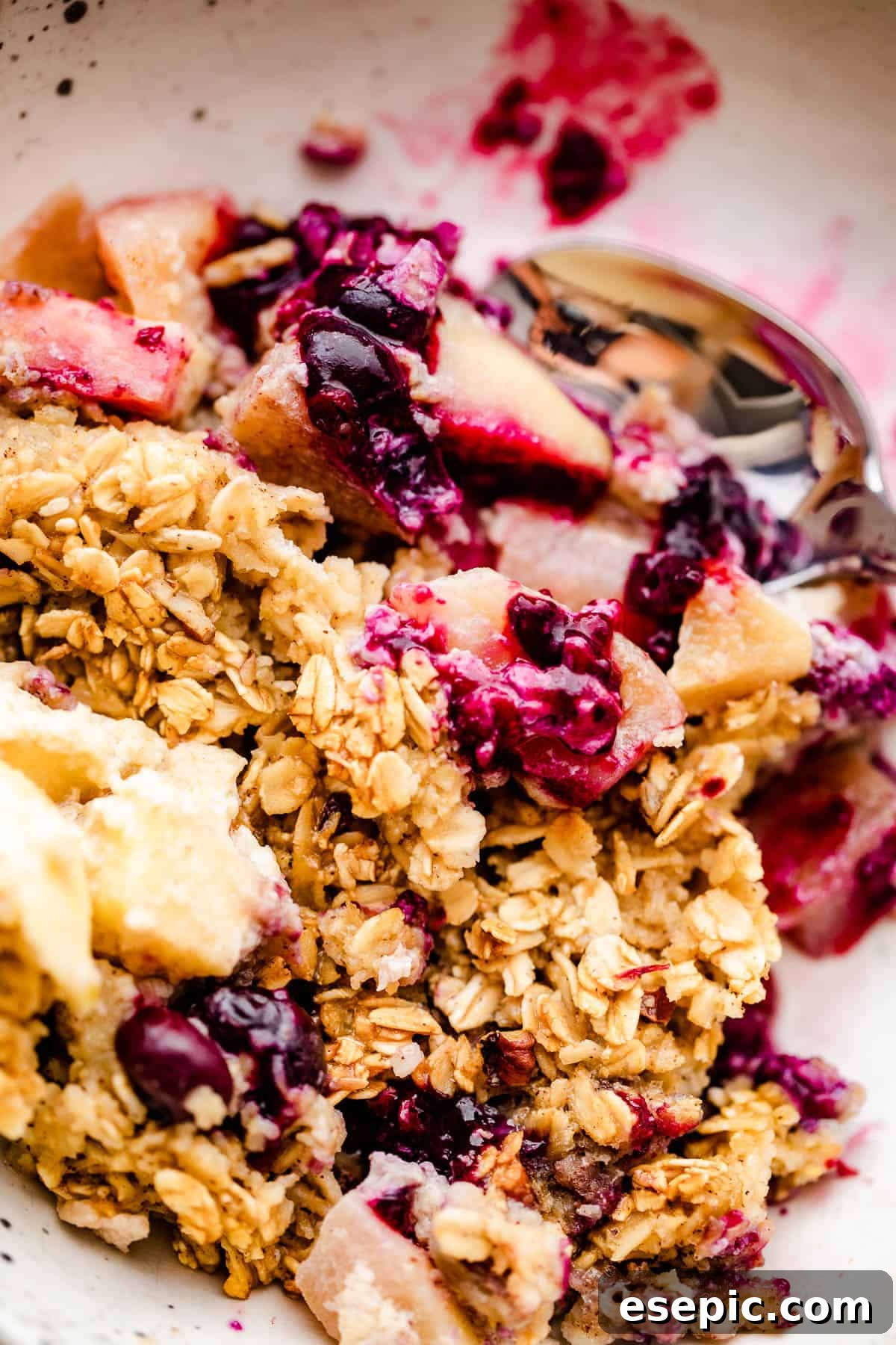 a scoop of apples and berries baked oatmeal served on a white plate.