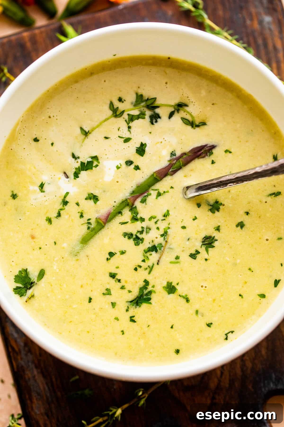 Simple Velvety Asparagus Soup 2 Cream of Asparagus Soup in a white bowl with a spoon inside.