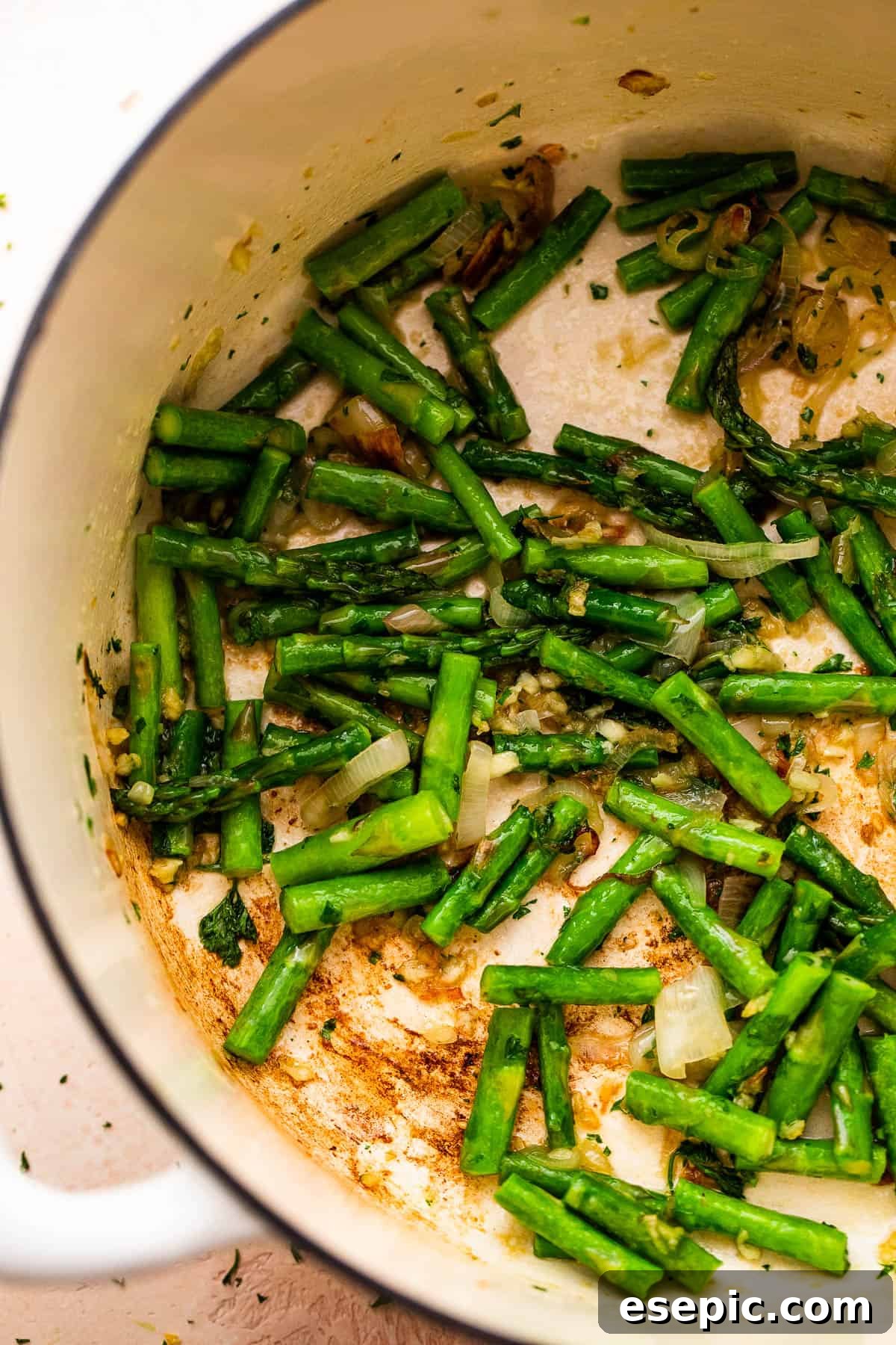 Simple Velvety Asparagus Soup 3 sauteeing asparagus spears inside a white dutch oven.