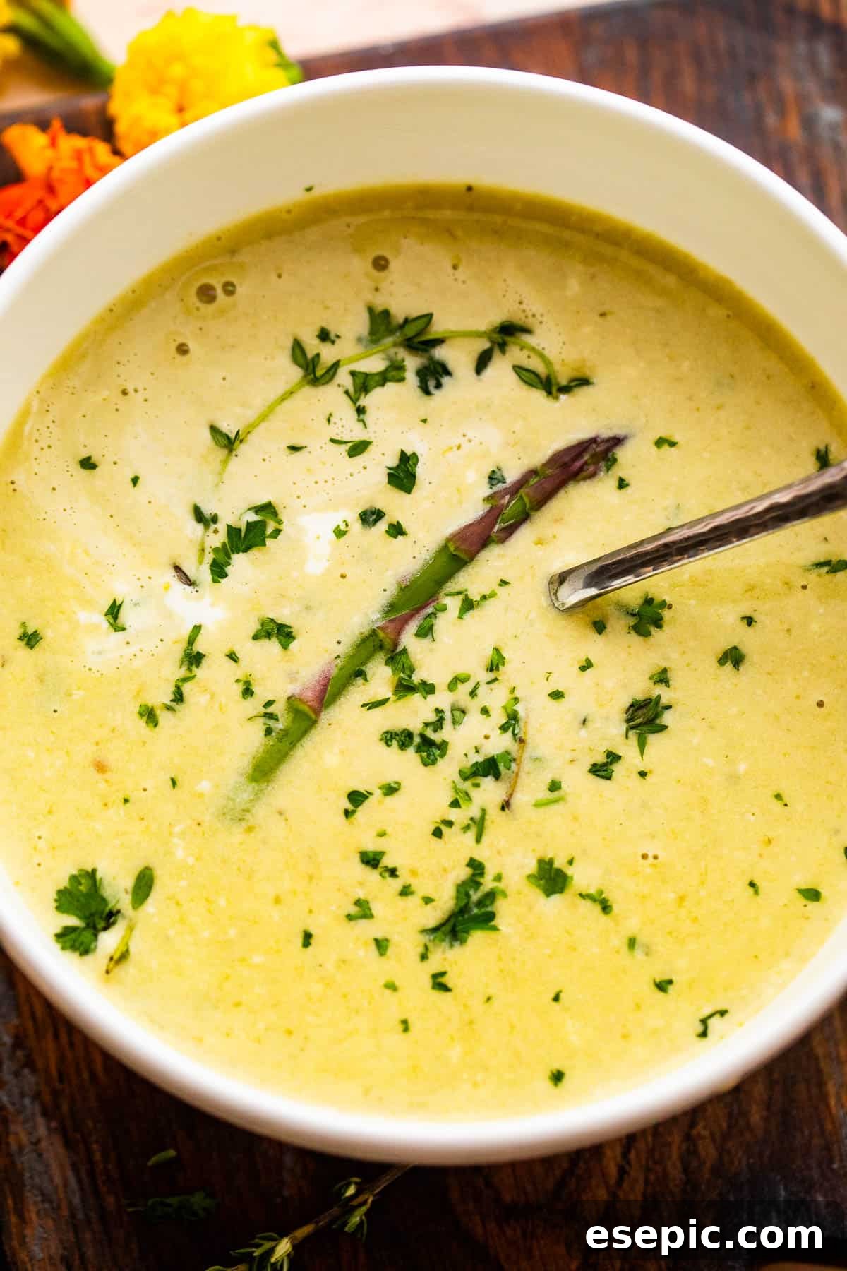 Simple Velvety Asparagus Soup 6 Overhead shot of Cream of Asparagus Soup served in a white bowl garnished with an asparagus spear and parsley.