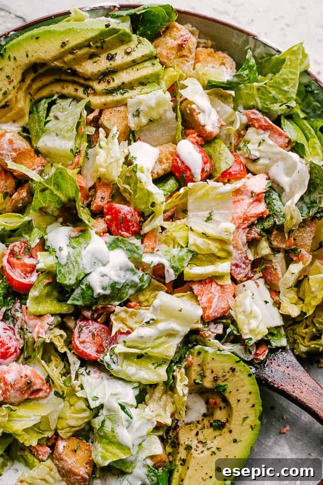 A large serving of Salmon BLT Salad, beautifully plated and thoroughly mixed with its creamy dressing, ready to be served.