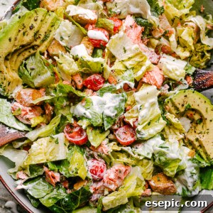 Salmon BLT salad plated with dressing mixed throughout