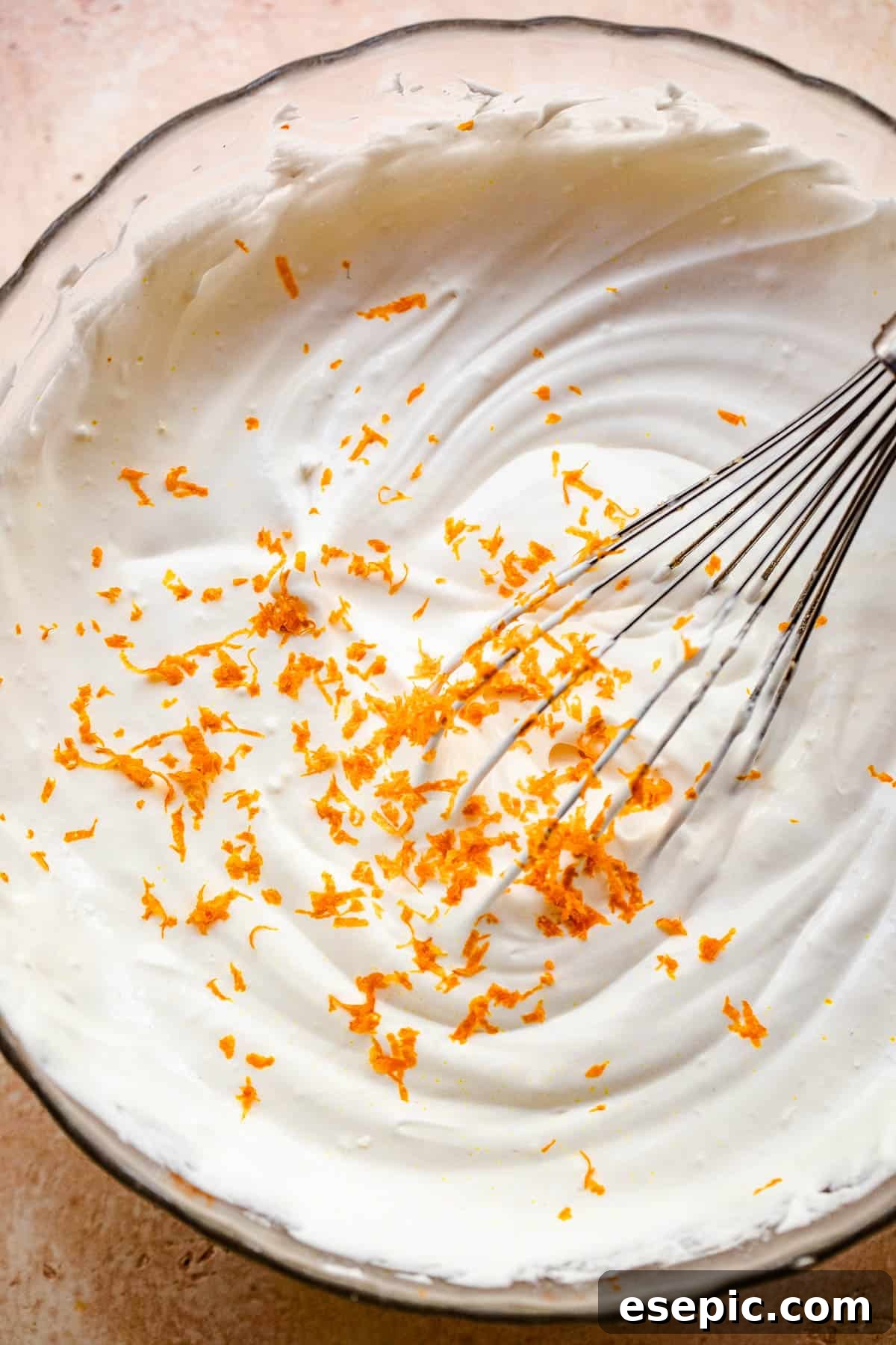 A hand whisking cream of coconut in a large mixing bowl as part of the preparation for a creamy coconut dip.