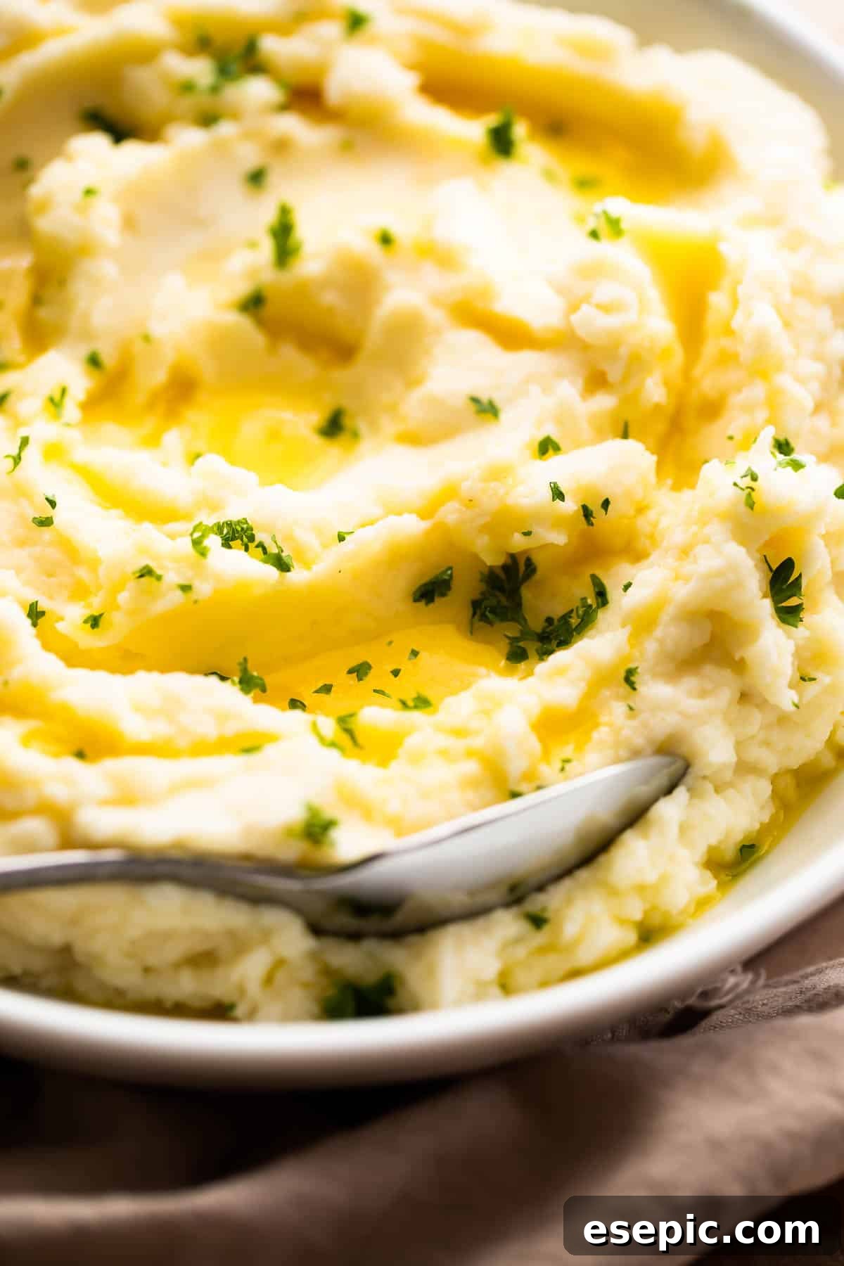 close up side shot of creamy mashed potatoes garnished with melted butter and parsley