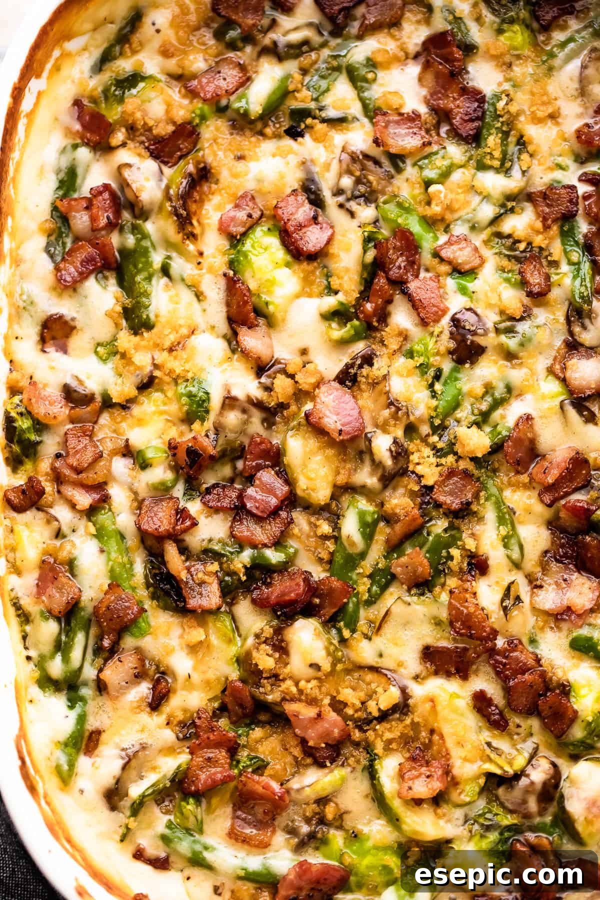 Close-up shot of a baked green bean casserole, showcasing its golden-brown crispy topping and savory diced bacon.