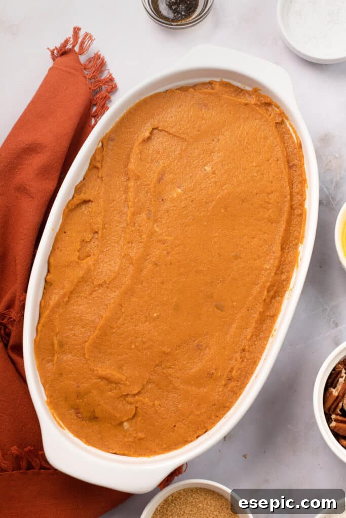 A baking dish with unbaked sweet potato casserole mixture spread inside.