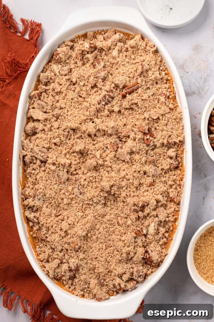 A baking dish filled with unbaked sweet potato casserole and topping.