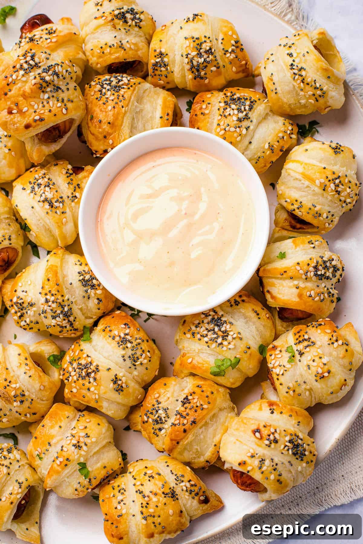 Platter of pigs in a blanket ready for serving. A platter of pigs in a blanket with a bowl of dipping sauce in the center.