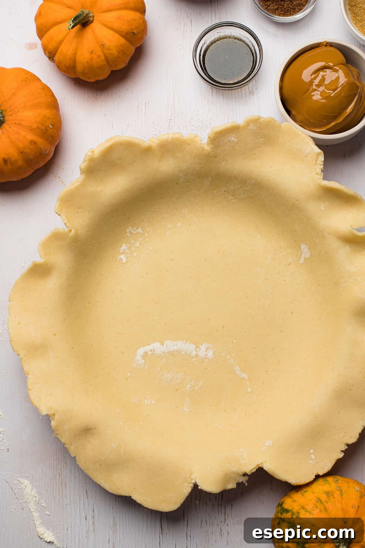 The process of lining a pie plate with homemade pie crust, a crucial step for achieving a perfect Pumpkin Pie from Scratch. A pie plate meticulously lined with freshly rolled homemade pie crust dough, with the edges still untrimmed, awaiting its final shaping.