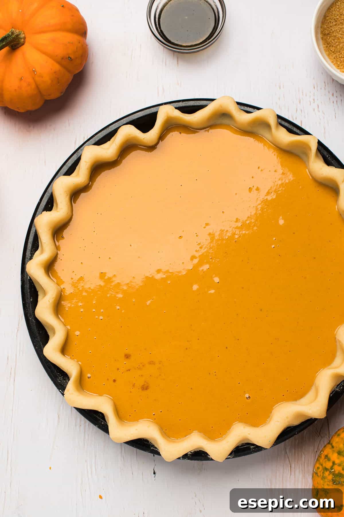 The penultimate step: a pie shell generously filled with the rich pumpkin mixture, poised for baking into a holiday masterpiece. An unbaked pie shell, expertly lined with homemade crust, filled to the brim with the smooth, orange pumpkin pie filling, ready for the oven.