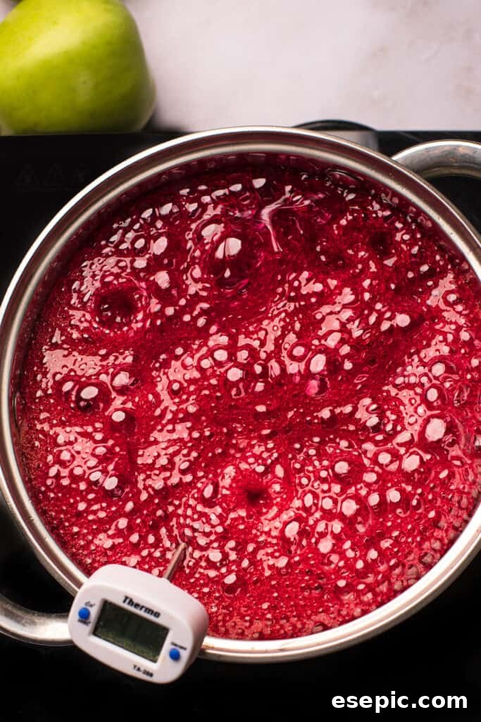 Sweet And Crunchy Candy Apples From Scratch 6 A saucepan of boiling sugar candy mixture that has been dyed red.