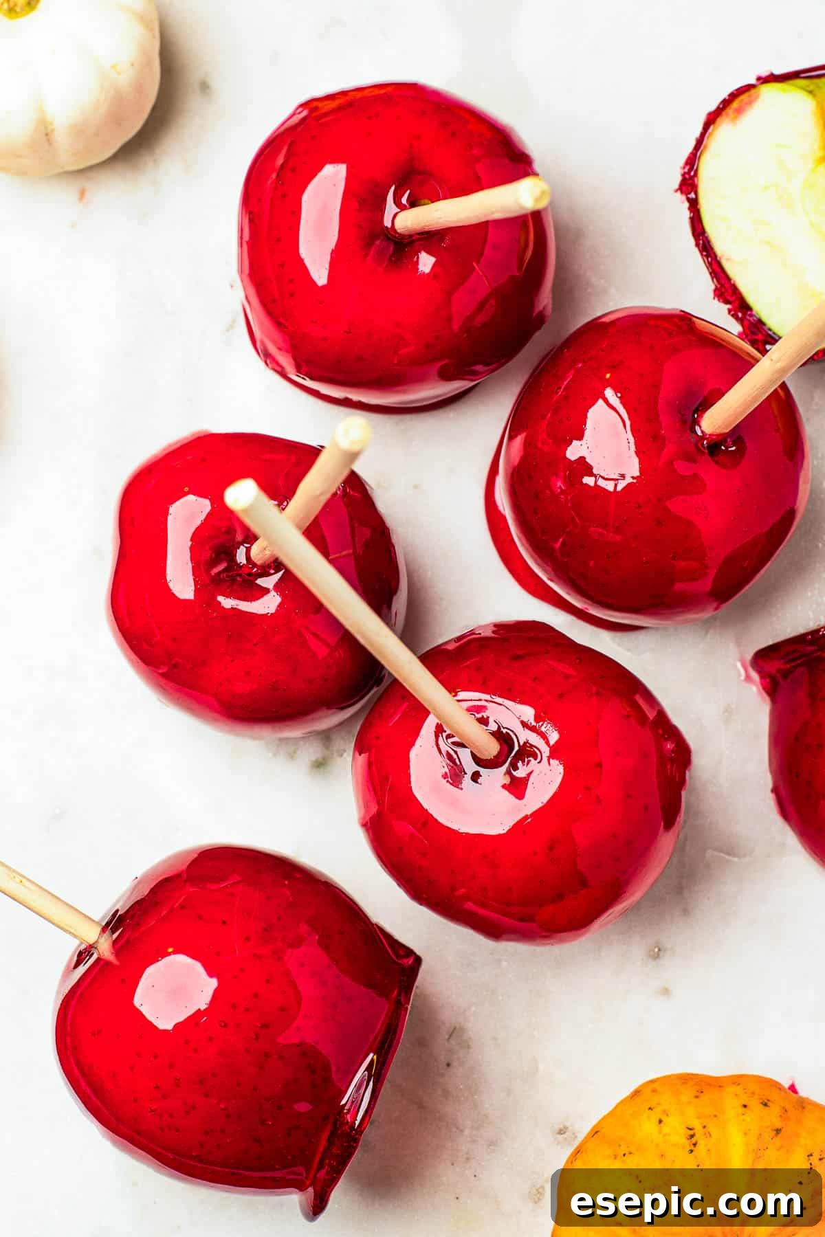 Sweet And Crunchy Candy Apples From Scratch 8 Several candy apples on a white cutting board. Plain Granny Smith apples and an orange fringed placemat in the background.