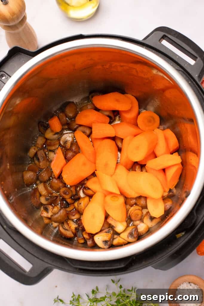 Quick and Classic Instant Pot Coq au Vin 6 Mushrooms and carrot pieces browning in the bottom of an Instant Pot.