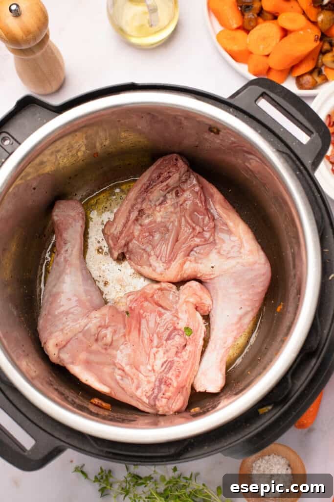 Quick and Classic Instant Pot Coq au Vin 7 Marinated chicken legs frying in the bottom of an Instant Pot.