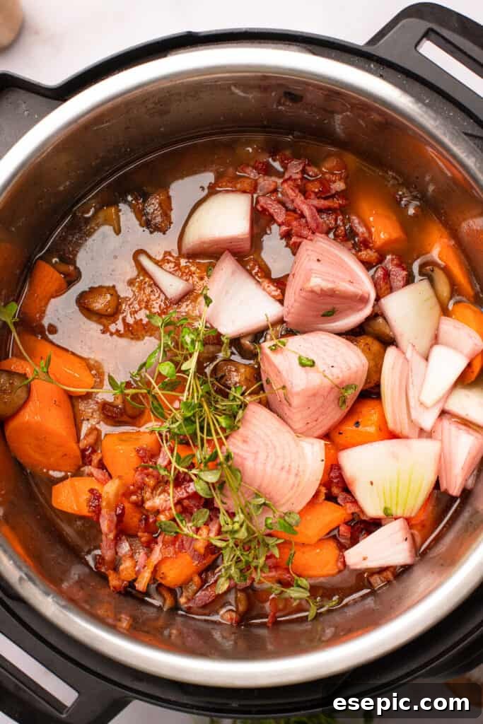Quick and Classic Instant Pot Coq au Vin 8 Overhead shot of onions, chicken thyme, and carrots in red wine sauce.
