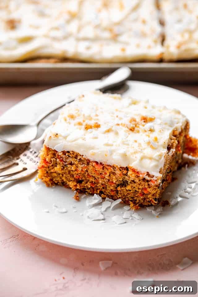 A perfectly frosted slice of carrot cake on a white plate with a fork.