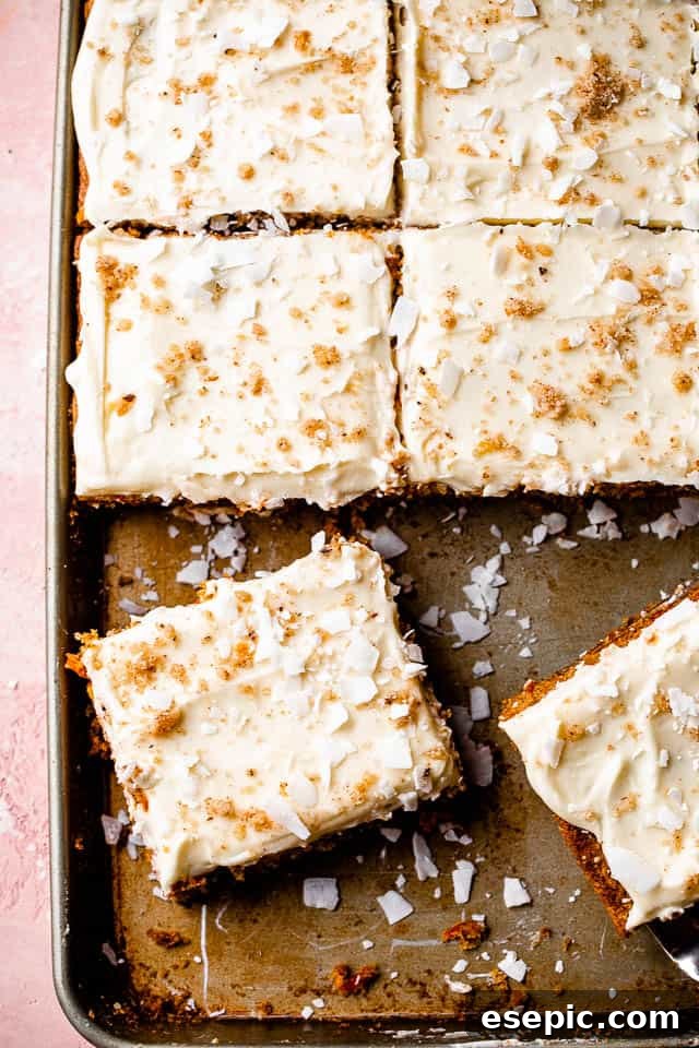 close-up of frosted carrot cake in a sheet pan, garnished with walnuts